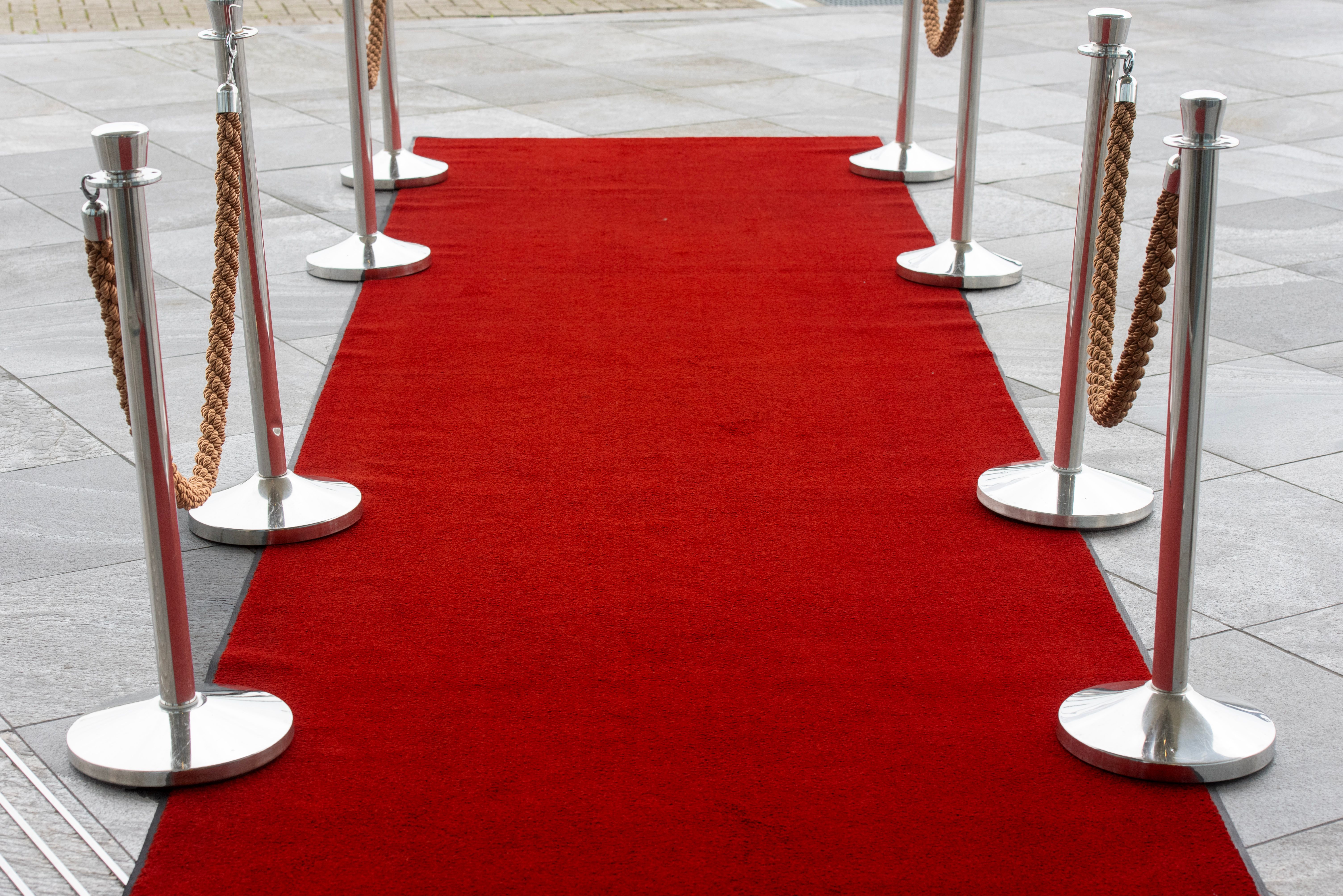 Red carpet entrance lined with stanchions, evoking an invitation-only event or product launch.